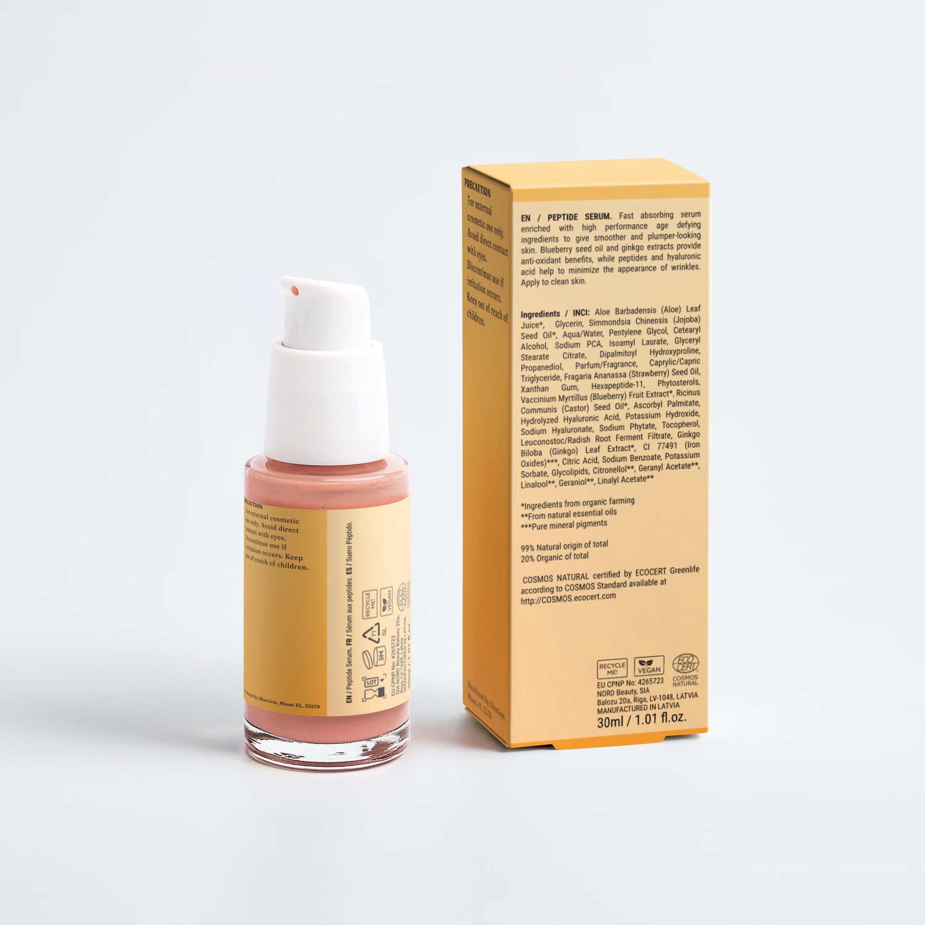 A small cosmetic bottle with a white pump and a peach-pink product inside, standing next to its tall yellow box on a clean light gray studio background.